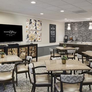 A modern cafe seating area with tables, chairs, wall art, and a coffee station.