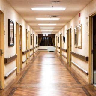 A well-lit indoor hallway with wooden flooring and multiple doors.