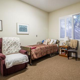 A cozy bedroom with a single bed, comfortable chair, and wall artwork.