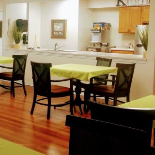 A cozy dining area with tables and chairs, adjacent to a kitchen.