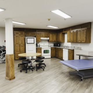 A modern recreation room with a kitchen area and table tennis setup.