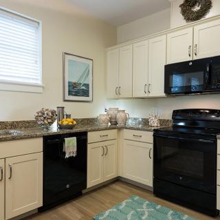A modern kitchen with white cabinets and black appliances.