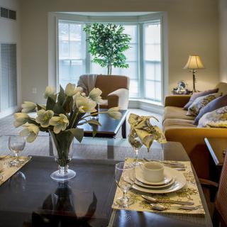 A cozy living room with a dining table adorned with flowers and elegant place settings, complemented by a comfortable seating area.