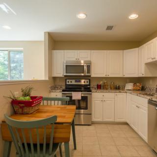 A modern kitchen with white cabinets, stainless steel appliances, and a small wooden dining table set.