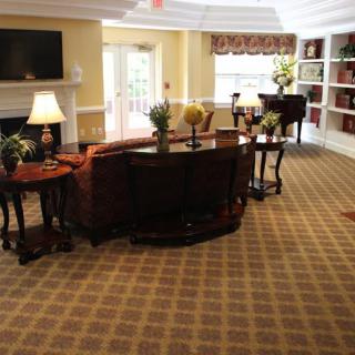 A cozy living room with carpeted floors, a piano, and elegant furniture.
