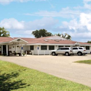 A view of a building with vehicles parked outside under a partly cloudy sky.