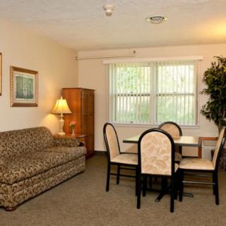 A cozy living space featuring a sofa, dining table with chairs, and a tall cabinet next to a window.