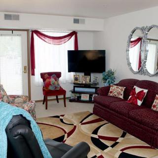 A cozy living room with a burgundy sofa, patterned rug, and elegant decor.