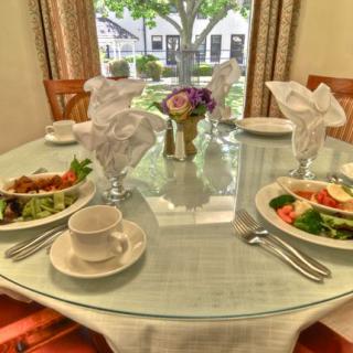 A neatly set dining table with salads, cups, and a flower centerpiece.