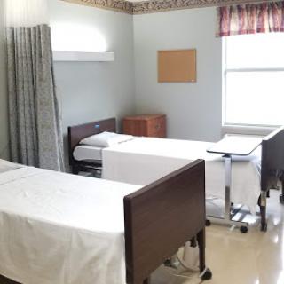 A tidy hospital patient room featuring two beds and a warm, inviting atmosphere.