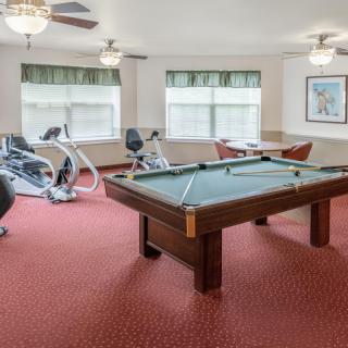 A game room featuring a pool table and exercise equipment with a carpeted floor.