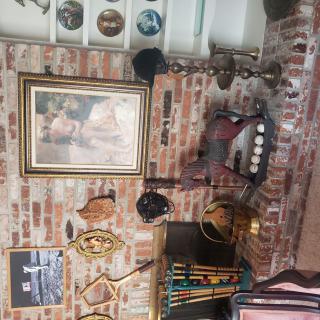 A cozy room with a brick wall adorned with paintings and vintage decorations around a fireplace.