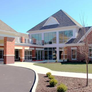 A modern brick building with large windows and a landscaped driveway.