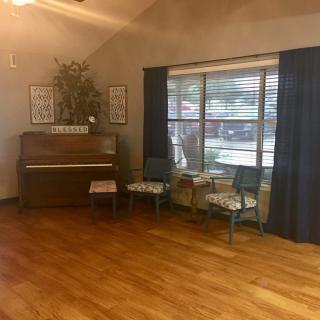 A cozy room with a piano and chairs by the window.