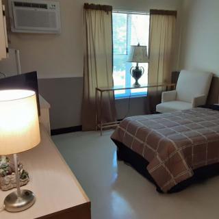 A cozy bedroom with a bed, chair, and lamps.