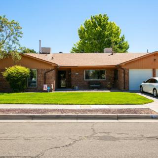 A suburban brick house with a well-maintained lawn and attached garage.