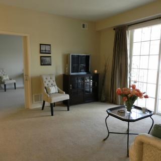 A cozy living room with a television, chairs, and a coffee table adorned with flowers.