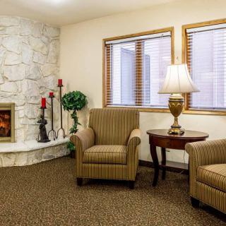 A cozy living room with a fireplace, two armchairs, and a side table with a lamp.