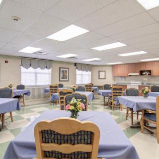 A spacious dining area with neatly arranged tables and chairs, featuring a warm ambiance and decorative flowers.