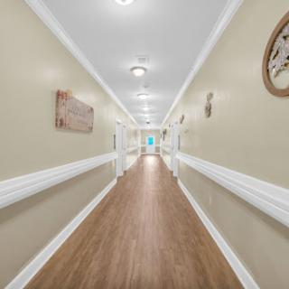 A well-lit hallway featuring neutral-colored walls and wooden flooring, creating a welcoming atmosphere.