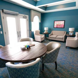 A cozy living room with a round table, armchairs, and a sofa in a brightly lit space.