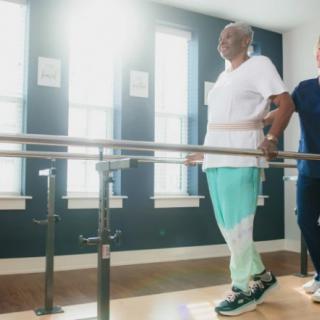 An elderly person undergoing physical therapy with the assistance of a therapist.