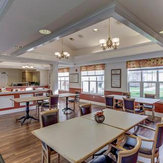 A spacious dining area with tables and chairs, featuring chandeliers and wood flooring.