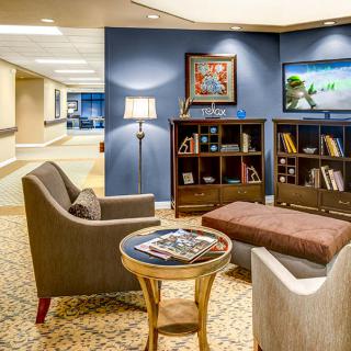 A cozy lobby with comfortable seating, bookshelves, and warm lighting.
