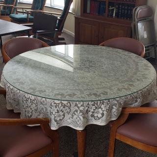 A round table with a decorative cover, surrounded by chairs in an office setting.