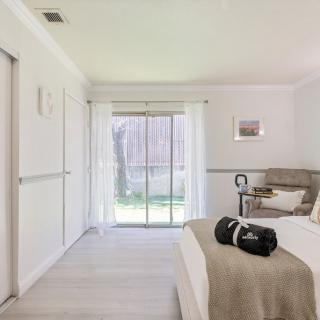 A minimalist and modern bedroom with ample natural light from a large sliding glass door.