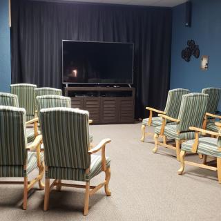 A cozy home theater setup with striped armchairs facing a large television.