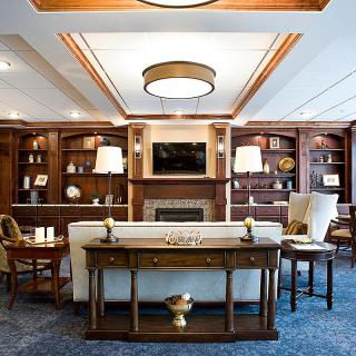 A cozy and elegant living room with a fireplace, surrounded by wooden bookshelves and modern furniture.