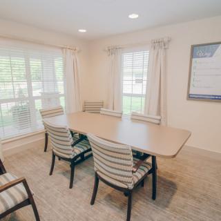 A bright and airy conference room with a table and chairs, featuring large windows and neutral decor.