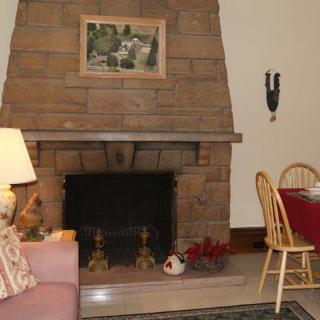 A cozy living room with a brick fireplace, couch, and dining area.
