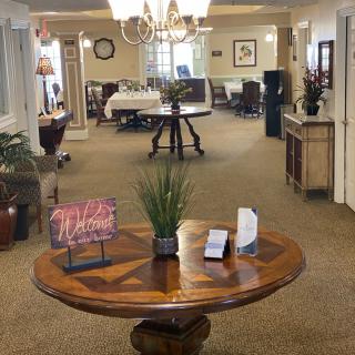 A well-decorated lobby with a central wooden table adorned with plants and brochures, leading to an open reception area.