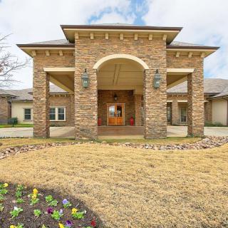 A brick residential house with a grand entrance and landscaped yard.