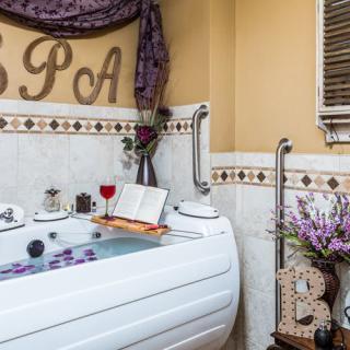 A cozy spa setting with a bathtub, candles, a glass of wine, an open book, and lavender accents creating a relaxing atmosphere.