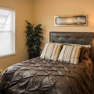 A cozy bedroom with a neatly made bed, decorative pillows, and wall art.
