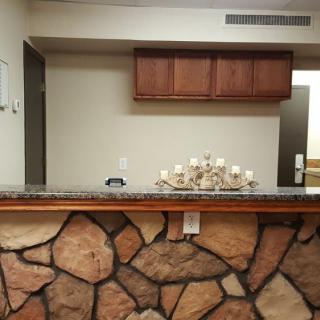 A reception desk with a stone facade and decorative candles, set in an interior space with wooden cabinets.
