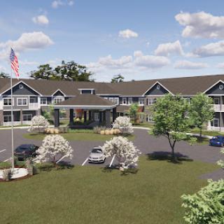 A welcoming hotel entrance surrounded by lush greenery and a clear blue sky.