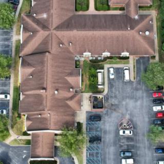 Aerial view of a building with a parking lot and several parked cars.