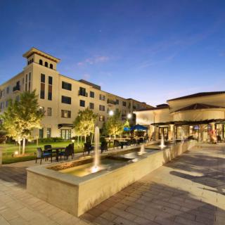 A luxurious hotel and resort with elegant architecture, featuring fountains and outdoor seating during the evening.