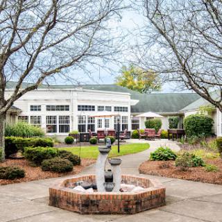 A serene courtyard featuring a fountain, surrounded by well-maintained landscaping and comfortable seating areas.
