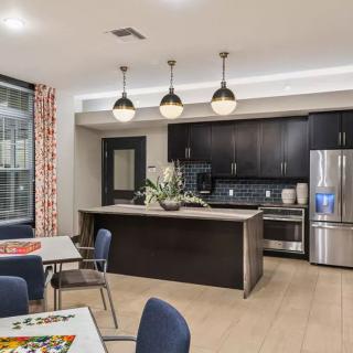 A modern kitchen with an island and pendant lighting, featuring stainless steel appliances and a dining area.
