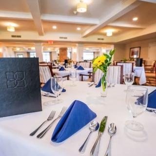 Elegant restaurant table setting with blue napkins and floral centerpiece.