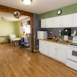 A cozy kitchen with white cabinets and a wooden floor, featuring an adjoining dining area.