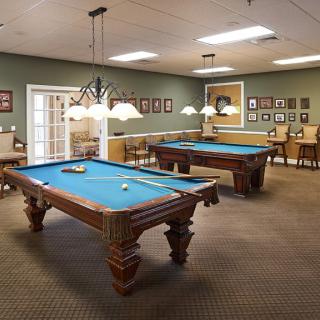 A spacious game room with two pool tables and ambient lighting.