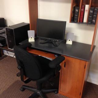 A neatly organized office desk with a computer monitor, speakers, and a chair.