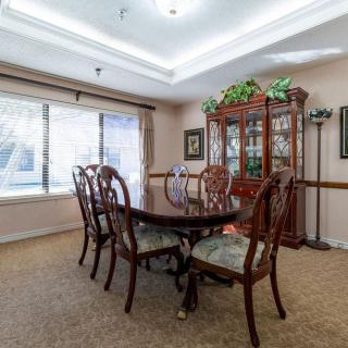 A traditional dining room with a wooden table, chairs, and a glass-front cabinet.