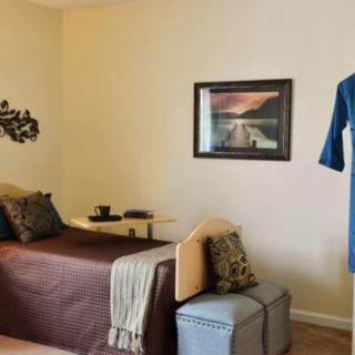 A cozy and minimalist bedroom with a brown bedspread, wall art, and simple decor.